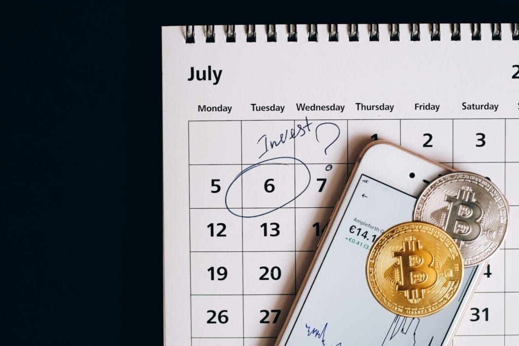 A calendar date marked "Invest?" next to a cellphone and two cryptocurrencies 
